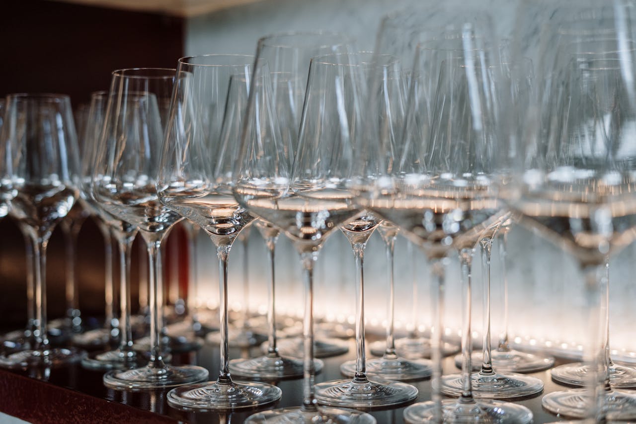 Row of crystal wine glasses neatly arranged on a shelf, highlighting elegance and luxury.